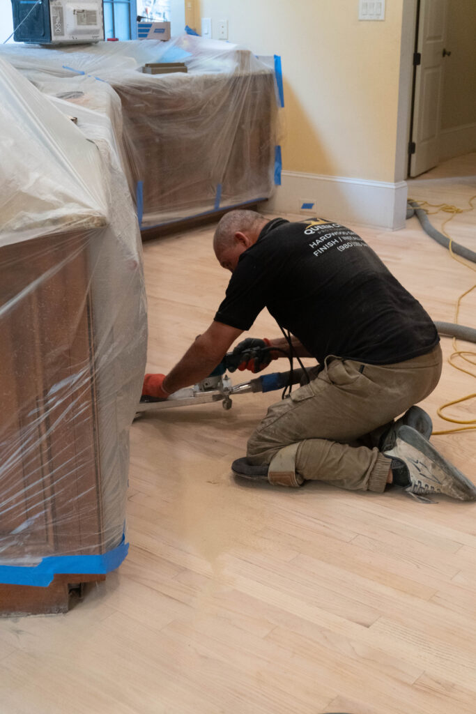 Guys sanding a wooden flooring on his knees